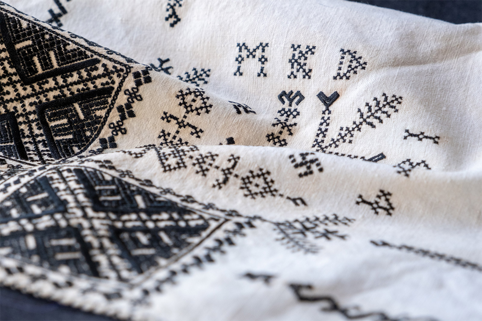 Närbild av hand som broderar med nål och tråd och visar det textila hantverket.