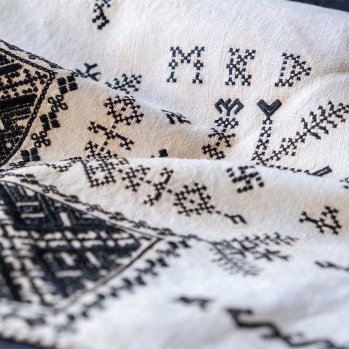 Närbild av hand som broderar med nål och tråd och visar det textila hantverket.